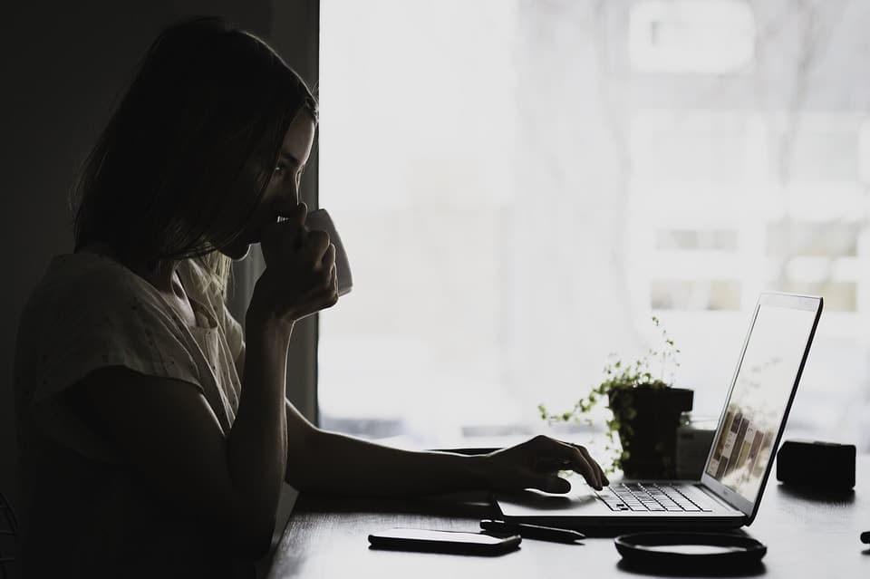 mulher bebendo cafe e olhando o computador
