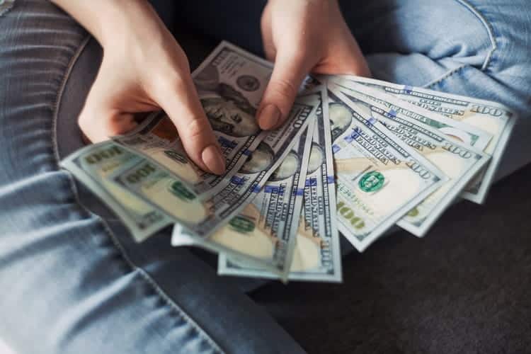 maos segurando muitas notas de cem dolares