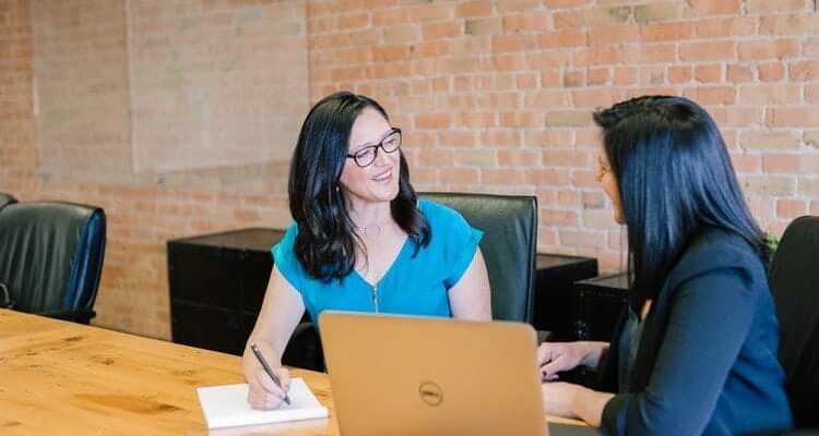 duas mulheres conversando num ambiente administrativo