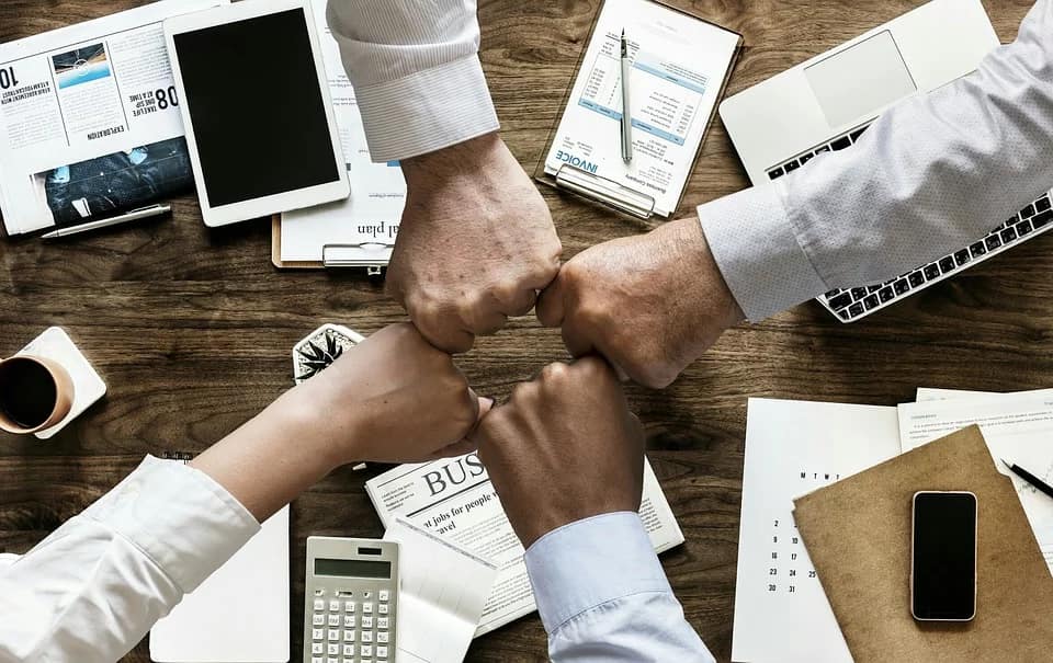 quatro pessoas fazendo fist bump numa mesa de reunioes