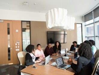 um grupo de pessoas sentadas ao redor de uma mesa com laptops mostrando diversidade